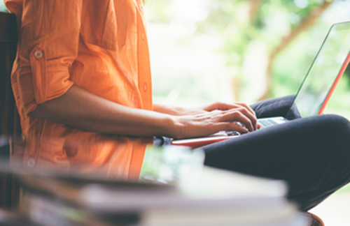 Young Person Sat On Bench Studying On Laptop