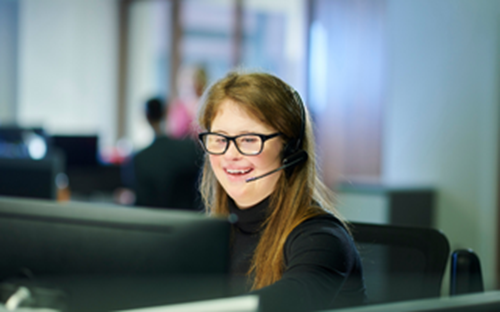 Lady on the computer with headset smiling