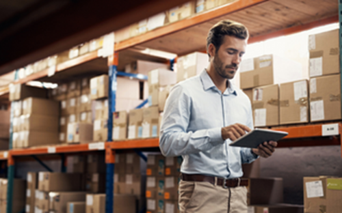 Man in a ware house checking stock on ipad