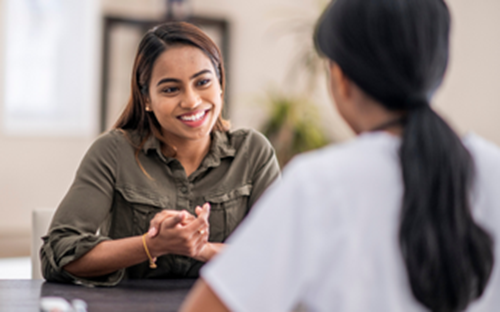 Two women talking to each other over a table